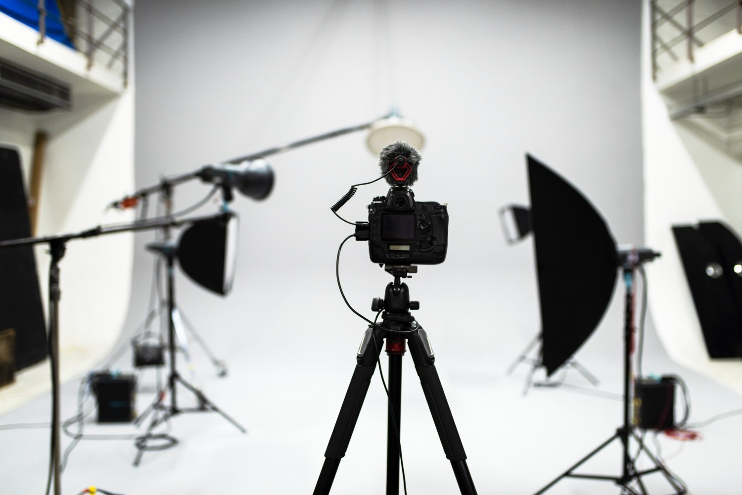 Interchangeable-lens camera with microphone on a tripod in a studio